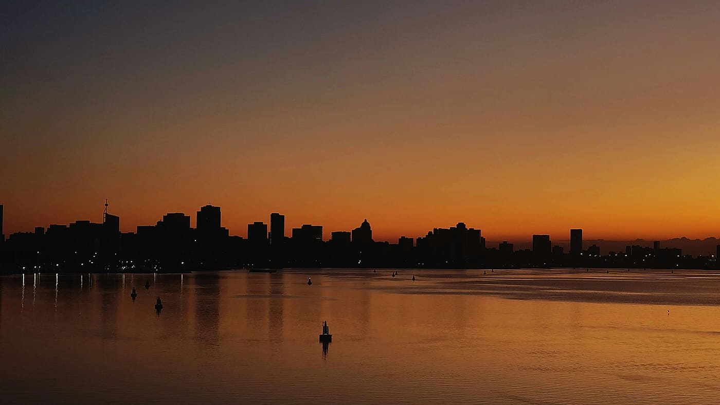 The Durban city skyline silhouetted across the bay at sunset
